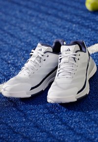 Bílé sportovní boty s námořnickými akcenty, síťovaným svrškem a strukturální podrážkou, se šňůrkami a designem loga se třemi pruhy.