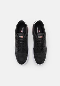 Baskets en cuir noir avec des semelles en caoutchouc blanches, dotées d'un bout rond, d'un laçage et d'un logo "Polo Sport" sur la languette et sur le côté.