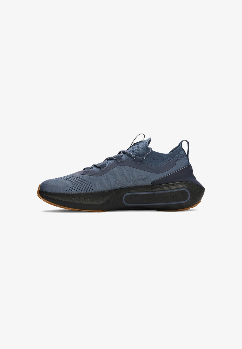 Baskets de sport bleu foncé avec dessus tricoté, semelle épaisse noire et languettes au talon et à la languette, vues de l'intérieur de côté.