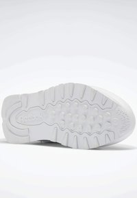 Fehér sneaker talp, textúrált gumitalppal, amely körkörös és barázdált mintázattal rendelkezik. Márkajelzés látható az oldalon.