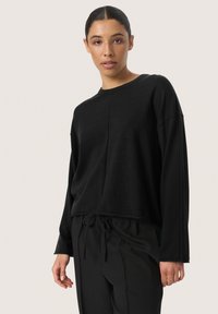 Black long-sleeve sweater with a round neckline, relaxed fit, and slightly cropped design. Made of soft fabric with a subtle texture.