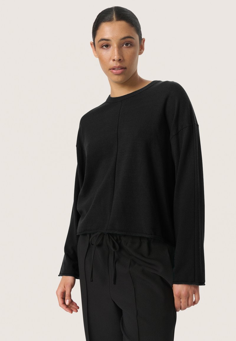 Black long-sleeve sweater with a round neckline, relaxed fit, and slightly cropped design. Made of soft fabric with a subtle texture.