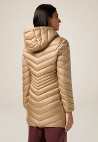 Beige pufferjack met een chevron-gequilt ontwerp, met een capuchon en lange mouwen. Glad, glanzend materiaal met een getailleerde silhoutte.