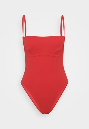 Costume da bagno intero rosso con sottili spalline, busto strutturato, texture liscia e aperture delle gambe alte. Senza motivi visibili o accessori.