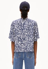 Kurzärmliges, verkürztes Oberteil im navyblauen und weißen Blumenmuster. Leichter Stoff mit lockerer Passform; hat einen runden Ausschnitt und eine weiche Textur.