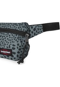 Marsupio grigio con motivo a macchie nere, dotato di un compartimento con cerniera e una tracolla intrecciata. Include una patch con il logo Eastpak.