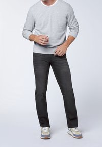 Felpa grigia con polsini a costine, jeans neri e scarpe da ginnastica multicolore. Design semplice, texture liscia e vestibilità su misura.