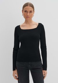 Schwarzer gerippter Pullover mit quadratischem Ausschnitt und langen Ärmeln, taillierter Schnitt, weicher Stoff, kombiniert mit dunklen Jeans. Einfach und elegant.