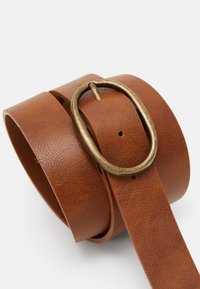 Brun læderbælte med en struktureret overflade, udstyret med en oval messingbuckle og flere huller til justering.