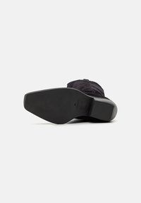 Black shoe sole with a smooth, flat design; rubber material; textured fabric upper with subtle stitching; minimal branding detail.