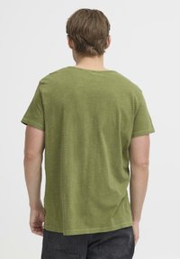 Koszulka z krótkim rękawem i okrągłym dekoltem, wykonana z mieszanki bawełnianej w stonowanym zielonym kolorze, o luźnym kroju i prostym dole. Charakteryzuje się subtelną fakturą i brakiem grafik.