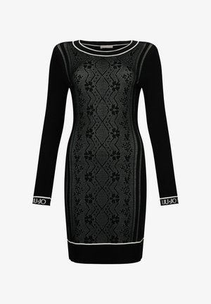 Robe noire à manches longues avec un motif en tricot géométrique, accents blancs au niveau du col et des poignets, et une coupe ajustée. Logo de la marque affiché.