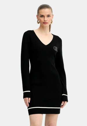 Vestito nero a coste con scollatura a V, maniche lunghe e dettagli a strisce bianche ai polsini e all'orlo. Presenta un logo ricamato sul petto.