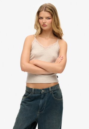 Top a canottiera rigata beige chiaro con pizzo sul collo, abbinato a un paio di jeans in denim blu scuro larghi. Design semplice e minimale.