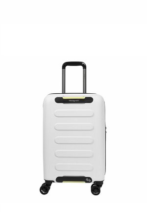 Valise cabine rigide blanche avec quatre roues noires et une poignée extensible noire et argentée, avant marquée avec "Hedgren."