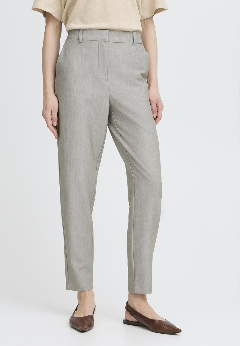 Šedé nohavice na míru s hladkou texturou, s rovný střihem a řasením vpředu. Kombinovány s hnědými balerínami.