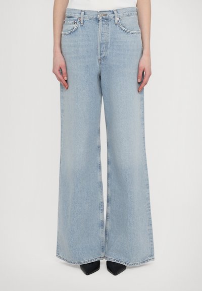Lyseblå, brede jeans lavet af denim; har høj talje, fem-lomme design og subtil fading langs stoffet.