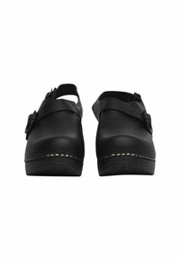 Zwarte klompen hebben een gladleren bovenkant, een achterband en een ronde neus. De zool heeft een duidelijke textuur en een gouden stiksel langs de rand.