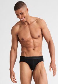 Slips neri realizzati in tessuto elastico, con una comoda cintura e un design aderente che si adatta al corpo.
