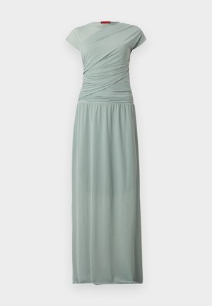 Lang, tettsittende kjole i lys grön stoff. Har en kort erme og en rynket bodice, som flyter ned til en samlet, elastisk midje.