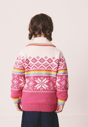 Ružový pletený sveter s bielym geometrickým vzorom a dúhovými pruhmi na golieri a manžetách. Žebrovaný lem a manžety pre lepšie prilnutie.