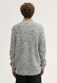 Pull en tricot gris et blanc avec un col montant, coupe décontractée et motif texturé ; manchons longs et poignets côtelés.