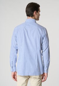 Camicia a maniche lunghe a righe blu e bianche con colletto a punta, polsini con bottoni e orlo curvo, realizzata in tessuto leggero.
