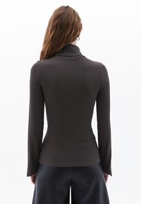 Langsleeve, donkerbruin geribbelde top met een aansluitende silhouet en een zachte textuur; met een omgeslagen kraag en een gestroomlijnd ontwerp.