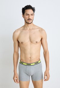 Szürke pamut boxer alsónadrág fekete és neon sárga Puma derékkal, szoros illeszkedéssel és mérsékelt hosszal. Simább textúra, minimalista dizájn.