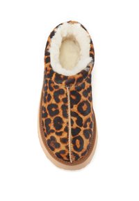 Pantoufles à imprimé léopard avec une douce doublure en fausse fourrure blanche et une semelle extérieure en caoutchouc marron clair. Bout arrondi et détails de couture minimalistes.