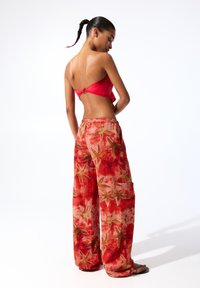 Rode bloemenpatroon wijdneklijnen met een elastische tailleband en zijzakken, gecombineerd met een rode cropped top met een knoopdetail.