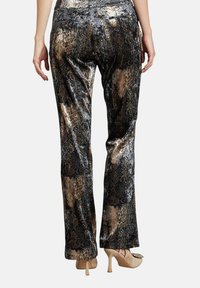 Pantaloni in stampa pitone metallizzato caratterizzati da una superficie lucida e testurizzata in tonalità oro, nero e bronzo. Design a gamba dritta, vita aderente.