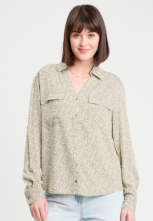 Chemise boutonnée imprimée vert clair avec de grandes poches sur la poitrine, un décolleté en V et des manches longues arborant un motif géométrique subtil.