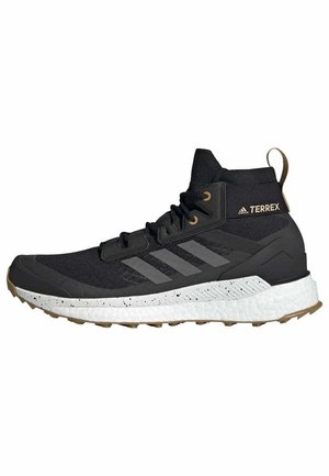 Czarny but trekkingowy Adidas Terrex z cholewką sięgającą do połowy wysokości, z białą, nakrapianą podeszwą i brązowym spodem, wyposażony w sznurowanie oraz pętlę z tyłu.