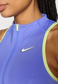 Αθλητικό τοπ με φερμουάρ από ανοιχτό μωβ ύφασμα με λαχανί λεπτομέρειες. Διαθέτει μικρό μαύρο λογότυπο Nike στο στήθος και λεία υφή.