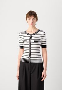 Cardigan tricoté noir et blanc à rayures avec des manches courtes, un col rond, une fermeture à boutons sur le devant et deux poches poitrine avec des accents dorés.