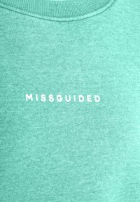 Mintgrön sweatshirt gjord av mjuk, texturerad tyg, med ribbad halsringning och "MISSGUIDED" tryckt i vitt på framsidan.
