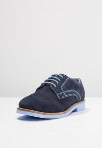 Scarpa in suede blu navy con accenti azzurri, caratterizzata da una punta tonda, design con cinque occhielli per lacci e suola in gomma azzurra.