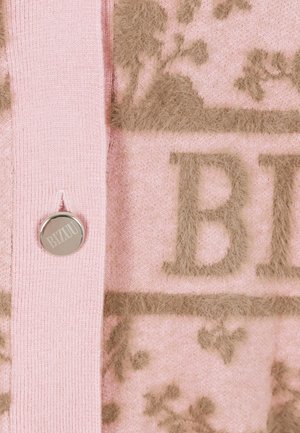 Różowy sweter z dzianiny z puszystymi brązowymi wzorami kwiatowymi i srebrnym przyciskiem z logo. Tekstura jest miękka z wyraźnymi akcentami.