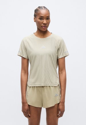 Light khaki athletic top with short sleeves and subtle texture, featuring a reflective logo on the chest and matching shorts.