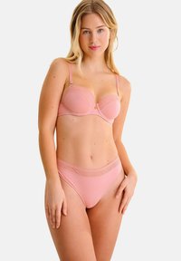 Ensemble de lingerie rose avec un soutien-gorge lisse ornée de coutures décoratives et d'armatures, associé à un slip taille basse assorti avec une ceinture à motif.