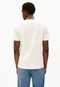 Witte katoenen t-shirt met korte mouwen, ronde halslijn en een ontspannen pasvorm. Achterstevoren gedragen, met een minimalistisch ontwerp en strakke lijnen.