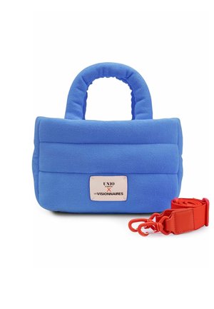 Sac à main matelassé bleu avec des poignées arrondies et une étiquette blanche, accompagné d'une bandoulière rouge vif amovible avec crochets sur fond blanc.