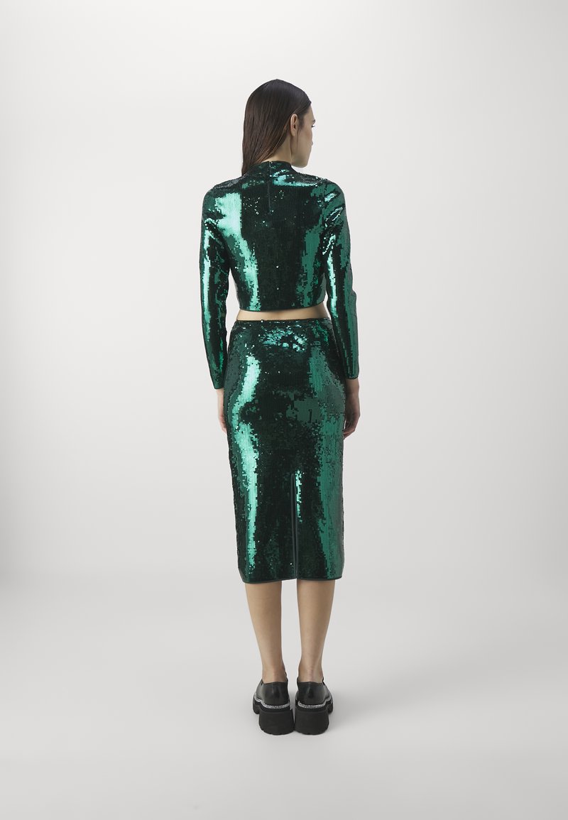 Zielono-szmaragdowy zestaw składający się z dwóch części, wykonany z materiału z cekinami. Posiada krótki, długi rękaw top oraz dopasowaną spódnicę do kolan.