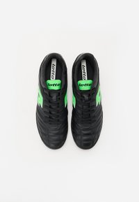 Black athletic shoes with a textured surface, featuring green accents and a logo. Lace-up design with a padded collar for comfort.