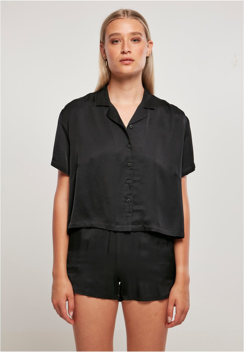 Camicia nera in satin a maniche corte con vestibilità rilassata, abbinata a pantaloni corti coordinati. Texture liscia e design corto.