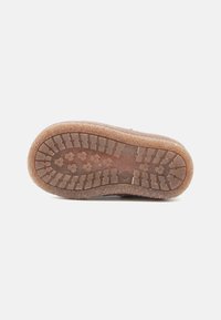 Suela de zapato de goma con una superficie texturizada y con patrón; presenta una banda de rodadura circular y lineal para tracción; color marrón.