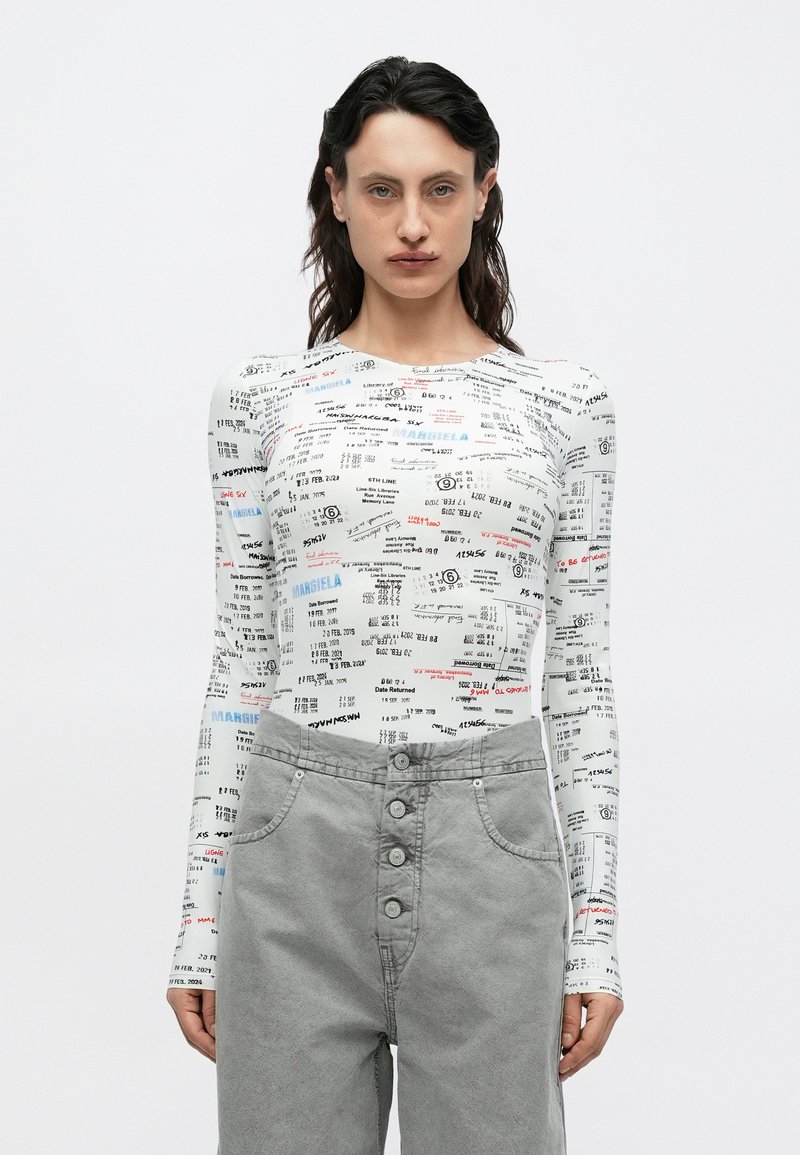 Dlhý rukávový body v bielej farbe, potlačený rôznymi textami a vzormi v červenej a modrej farbe. Kombinovaný so sivými nohavicami s vysokým pásom a zapínaním na gombíky.