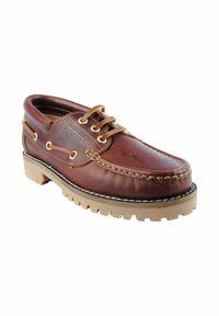 Zapato náutico de cuero marrón con costura elevada, ojales dorados y suela de goma con un patrón de agarre resistente.