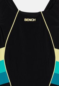 Maillot de bain noir avec des rayures multicolores (jaune, vert d'eau) et un design ajusté. Logo "BENCH" en jaune en haut au centre. Texture lisse.